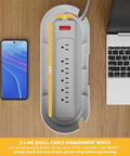 Top view of White Cable Management Box For Power Strips Up To 10.5 Inches with outlet and phone on wooden desk