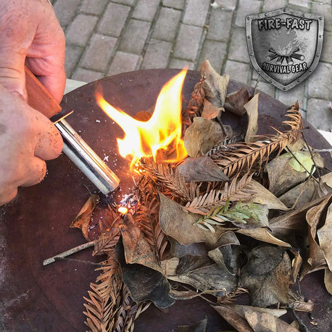Person using All Weather Survival Fire Starter with Magnesium Ferro Rod and Euro Ferrocerium to ignite dried leaves.