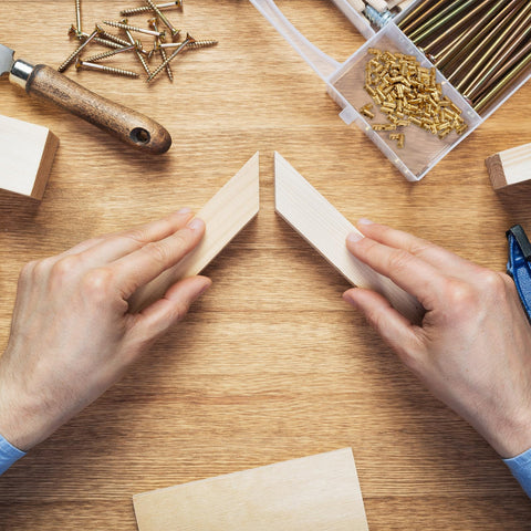 Hands holding wooden pieces with brass screws and Uxcell Invisible Barrel Hinges 50 Pcs 4x15mm Brass Concealed Hidden Hinges nearby.