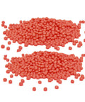 Two piles of red wax beads for waxing, close-up view on white background.