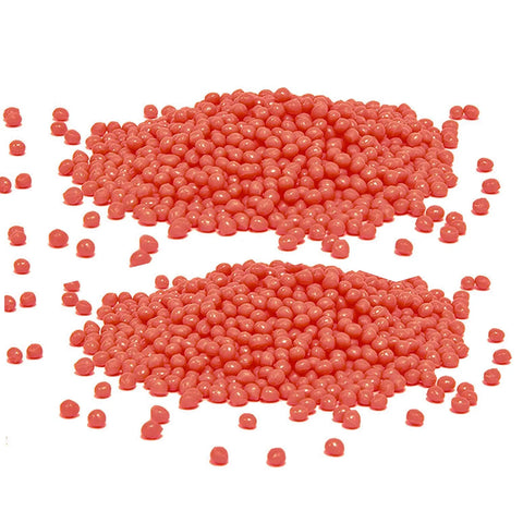 Two piles of red wax beads for waxing, close-up view on white background.