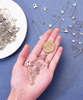 450 Pack Real Deal Iron Safety Clasp Pins For Crafting And Tailoring in hand with a coin for size reference.