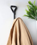 Heavy Duty Wrought Iron Coat Hook With A Distressed Bronze Look Hand Forged Wall Mount Rack Built Tough Rust Proof Construction hanging a tan coat