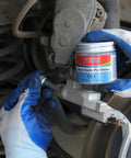 FOTU brake caliper guide pin grease 661 can held by blue-gloved hand near a metal brake caliper