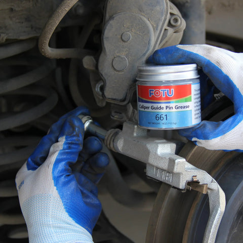 FOTU brake caliper guide pin grease 661 can held by blue-gloved hand near a metal brake caliper