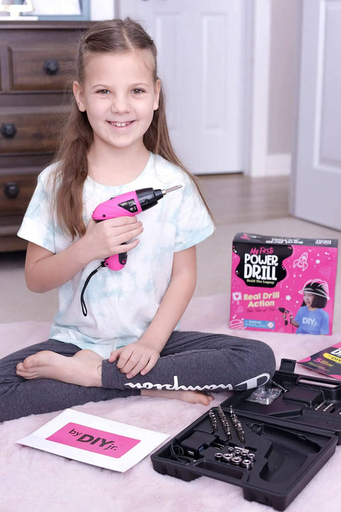 Girl holding Girls Power Drill Set With Realistic Drilling Action 60 Piece Tool Kit Rechargeable Cordless Pink Drill With LED Light