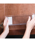 Hands installing Clear Plastic Wall Mount Organizer Shelf for Kitchen Bathroom Office Bedroom Garage and Craft Room 3 by 11 by 3.25 inches