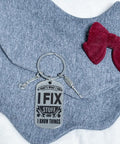 Thats What I Do I Fix Stuff And I Know Things Mechanic Keychain Gift For Maintenance Pros laid on grey fabric with red bow