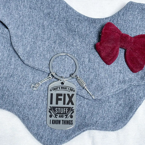 Thats What I Do I Fix Stuff And I Know Things Mechanic Keychain Gift For Maintenance Pros laid on grey fabric with red bow