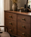 The Real Deal Natural Walnut And Antique Brass Cabinet Knobs Six Pack on a wooden dresser, showcasing round ball handles.