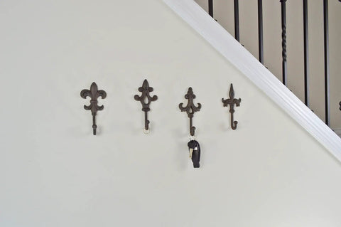 Built Like A Tank Cast Iron Wall Mount Key Hooks For Entryway And Garage Featuring Classic Fleur De Lis Charm Dark Brown, set of four on wall.