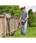 Man trimming grass along a wooden fence using AF100 String Trimmer Spool Replacement Pro Grade Compatible With Black And Decker