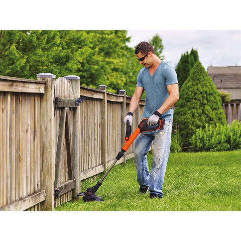 Man trimming grass along a wooden fence using AF100 String Trimmer Spool Replacement Pro Grade Compatible With Black And Decker