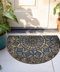 Semi-circular decorative outdoor doormat with intricate pattern near an entrance, surrounded by potted plants.