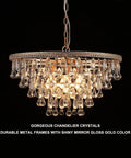 Gold Crystal Raindrop Chandelier Pendant Light For Dining And Living Rooms with brass gold frame, lit up against dark background.