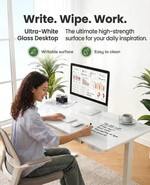 Glass Standing Desk With Drawer 37 X 22 Inches Adjustable Height With Four Preset Levels One Piece Tempered Glass Top White Ergonomic Home Office Desk For Standing Work with a woman writing on the surface.