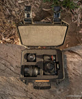 Vault V100 Tough As Nails Multi Purpose Hard Case with Foam holding camera gear, open on wood with outdoor background.
