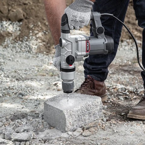 Person using Beast 1200W Electric Rotary Hammer SDS Plus Drill With Swivel Handle on concrete block outdoors