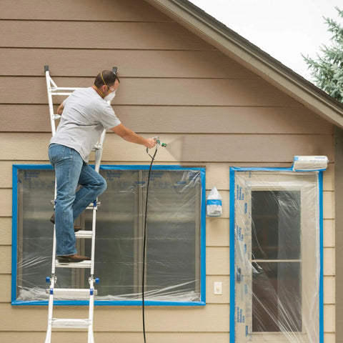 A person using a mobile airless paint sprayer on home siding while standing on a ladder for Crush Huge Painting Jobs Straight Up With Heavy Duty Mobile Airless Paint And Stain Sprayer Cart For Butter Smooth Finishes On Home Exteriors Sheds And Fence Panels.