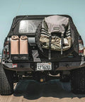 Truck with two sand-colored Portable 5 Gallon Military Style Water Jug For Camping And RVs Sand Colored Plastic Beverage And Hydration Dispenser.