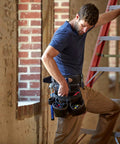 Worker wearing durable oil tanned leather tool rig with large capacity for hand tools and fasteners on a construction site ladder
