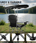 Black folding camping chair with canopy shade and cup holders, beach ready with armrests, lakeside view, UPF 50 sun shield.