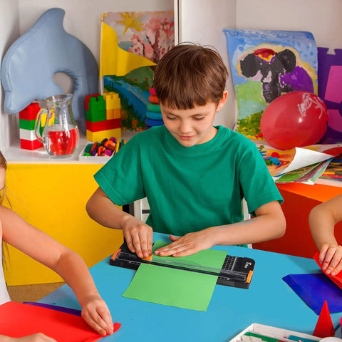 Child using 12 Inch Titanium A4 Paper Cutter With Automatic Safety Guard And Side Ruler for craft in classroom setting
