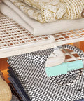 Closet Shelf Organizer Metal Storage Rack for Home Wardrobes with folded linens on industrial iron frame.