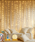 Upgraded Tangle-Free Warm White USB Curtain Lights With 200 LEDs, 6.6Ft By 6.6Ft Window String on wall, remote in hand