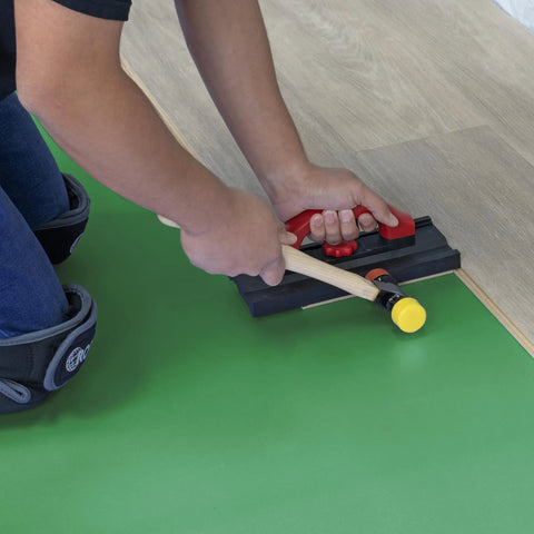 Installing Top Shelf Premium Acoustical Underlayment Roll For Hardwood Floors 100 Square Foot Sound Dampening Foam with a mallet.