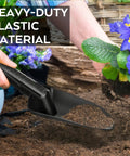 Heavy Duty Black Sand Scoop And Shovel digging soil beside flowers, highlighting its weather resistant and rustproof properties.