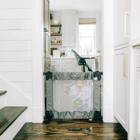 Child behind Go With Me Portable Mesh Baby Gate For Hallways And Doorways Expandable From 30 To 48 Inches Folding Safety Gate