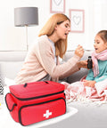 ALSLEA red first aid bag (12 x 9 x 7 in) with white cross, portable medical kit on table beside sofa.