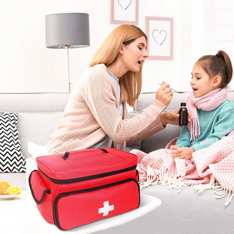 ALSLEA red first aid bag (12 x 9 x 7 in) with white cross, portable medical kit on table beside sofa.