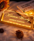 Custom Desk Name Plate With LED Wood Base, Light Up Acrylic Name Plate For Desk And Office Sign, Personalize With Name Or Title displayed on soft fabric with decorative items and books