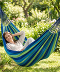 Woman relaxing in Ultra Comfy Cotton Hammock Portable Camping Hammock For Hanging With Tree Straps Sturdy Garden Fabric Hammock