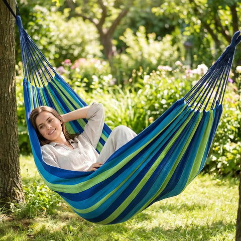 Woman relaxing in Ultra Comfy Cotton Hammock Portable Camping Hammock For Hanging With Tree Straps Sturdy Garden Fabric Hammock