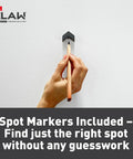 Hand holding pencil against wall using Claw 65 Lb Drywall Picture Hangers With Spot Markers No Studs Needed 3 Pack Heavy Duty Hangers.
