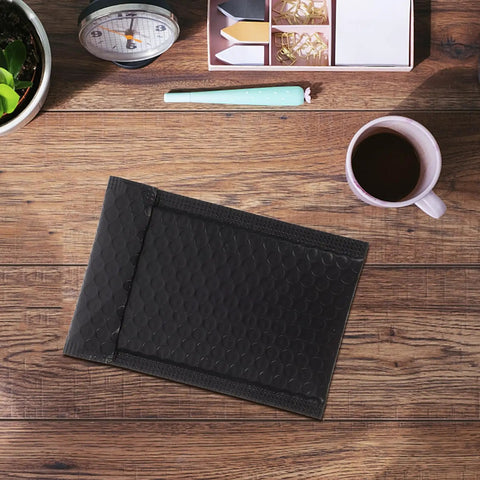 Padded Bubble Mailers Self Seal Envelopes 12x18 And 4 Inch Thickened Black Shipping Bags on a wooden desk with coffee