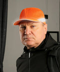 Person wearing an orange Bump Cap Safety Hat For Work 5 Pack, Reflective Neon Mesh, Lightweight ABS Shell, indoors.