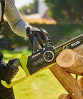 User operating Hella Smooth 18V Brushless Battery Chainsaw With 30Cm Oregon Bar cutting wood logs in yard.