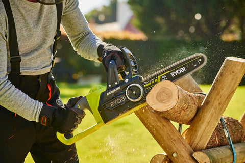 User operating Hella Smooth 18V Brushless Battery Chainsaw With 30Cm Oregon Bar cutting wood logs in yard.