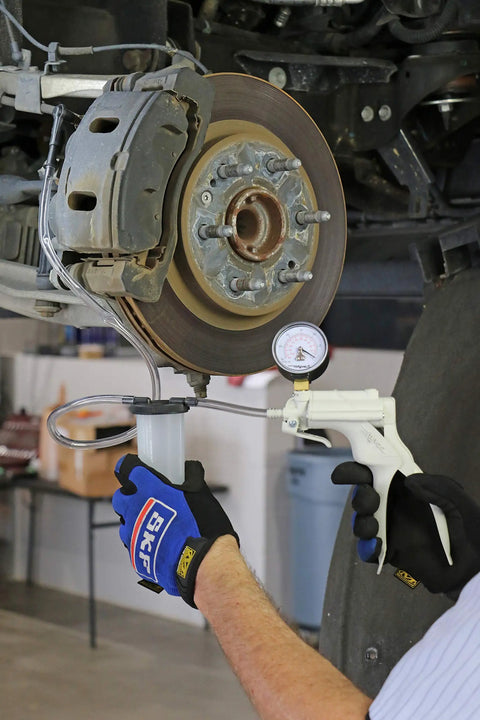 Heavy Duty Hand Vacuum Pump Brake Bleeder Kit With Gearless Diaphragm Gauge And Dead Simple One Finger Release being used on brake caliper.