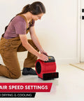 Woman adjusting Heavy Duty Three Speed Floor Fan With 156W 550 CFM Air Mover for quick drying and cooling in room