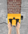 Hands using pro grade electric wall planer on brick surface for drywall prep and concrete smoothing.