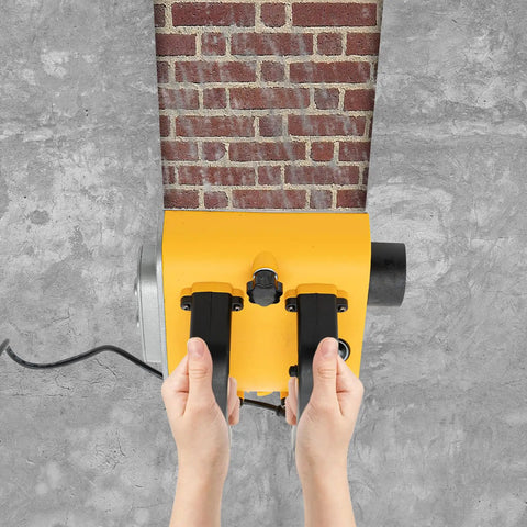 Hands using pro grade electric wall planer on brick surface for drywall prep and concrete smoothing.