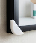 Pro Grade Protective Corner Guards for picture frames with durable plastic edge protector on black frame corner