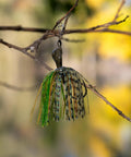 Weedless Bass Jig With Bladed Vibration Tech For Pike Walleye Muskie Six Color Lures Set on a branch. Chartreuse color visible.