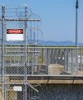 Chain-link fence with a warning portable first aid sign aluminum 8x12 inch wall art safety plaque for commercial workplace area.