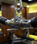 Close-up of Lat Bar Cable Machine Attachment with Full Rotation Rubber Grip, showing shiny steel and carabiner detail in gym setting.